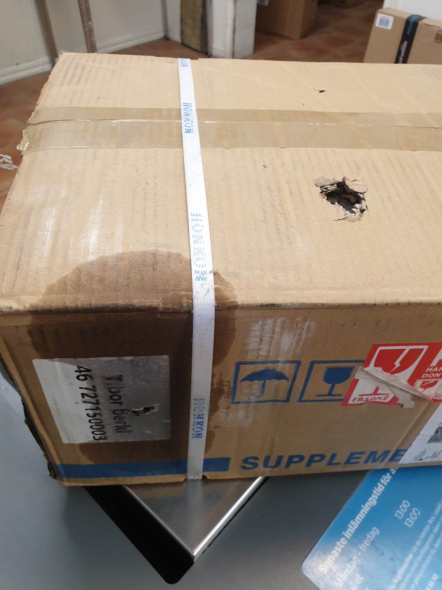 A big hole and some fluid leaking out to the cardboard box